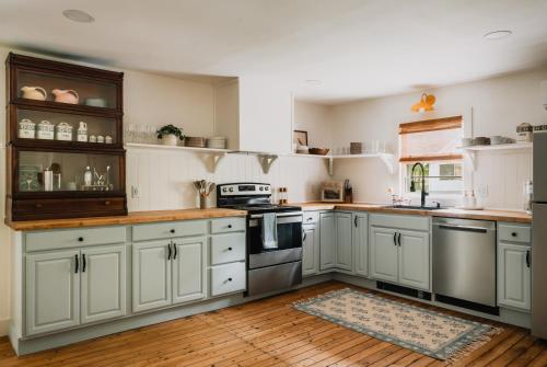 Il comprend une cuisine avec des placards blancs et du parquet. dans l'établissement Roebling House 1850s Cabin Hot Tub Fire Pit, à Lackawaxen
