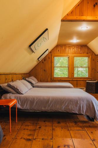 two beds in a room with wooden walls and windows at Breathtaking River Views The Hawks Nest Cabin in Glen Spey