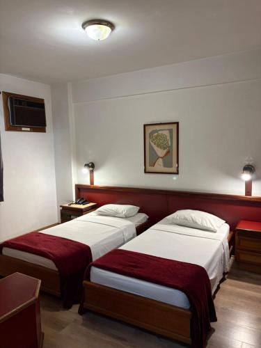 a hotel room with two beds and a tv at GoldMen Business Hotel Blumenau in Blumenau