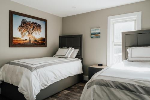 ein Schlafzimmer mit 2 Betten und einem Baumbild an der Wand in der Unterkunft Swan Pond Cabin Hot Tub & Firepit Retreat in Swan Lake