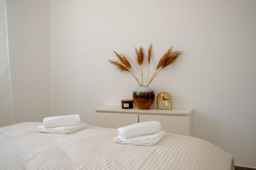 a bed with two towels and a vase with a plant at LALA & DAUGHTERS Apartment in Vrnjačka Banja