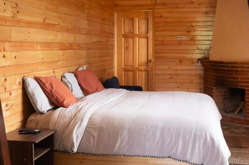 ein Schlafzimmer mit einem Bett in einer Blockhütte in der Unterkunft San José del Pacífico- Cabañas Camino al Cielo 1 in San Mateo Río Hondo