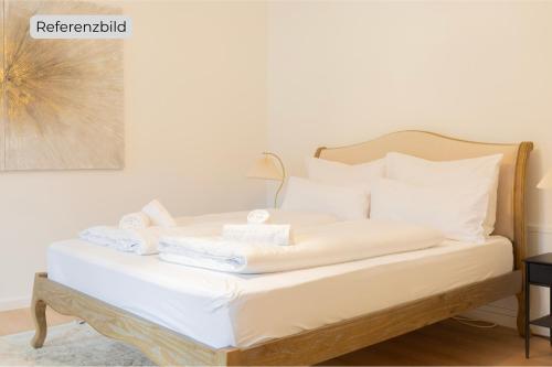 un lit avec des draps blancs et des serviettes dessus dans l'établissement ღLiboria I Aidling Panorama Stilvolles Ferienhaus mit Bergblick, à Riegsee