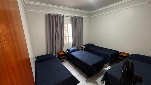 une chambre avec trois lits et une fenêtre dans l'établissement Casa de Temporada - Umuarama 2, à Uberlândia