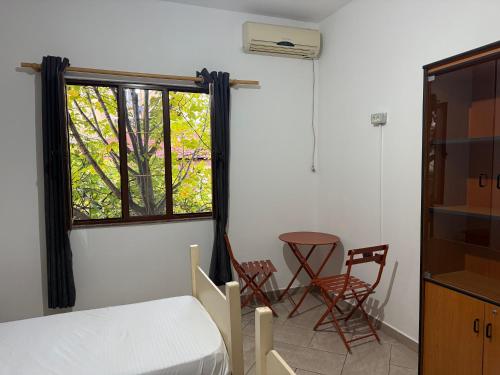 ein Schlafzimmer mit einem Bett, zwei Stühlen und einem Fenster in der Unterkunft Hostel Osho in Tirana