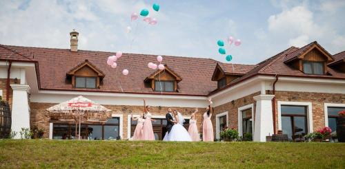 a bride and groom standing in front of a house with balloons at St Peter Vini in Svätý Peter