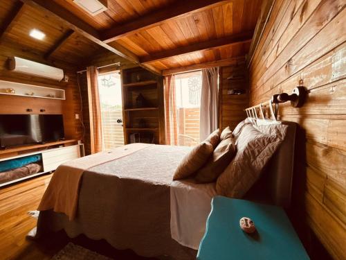 a bedroom with a bed in a wooden cabin at cabanas Aconchego dos Canyons in Praia Grande