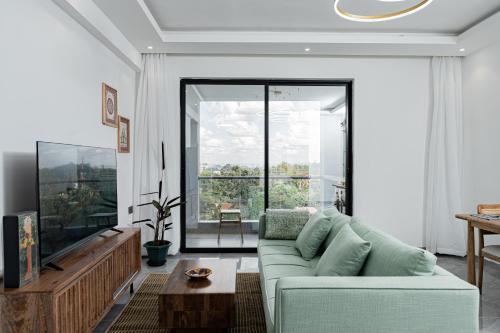 a living room with a couch and a large window at Diamond Ivy Two Bedroom Apartment, Swimming pool, gym, workspace ,Wonderiss Homes Kileleshwa Living in Nairobi