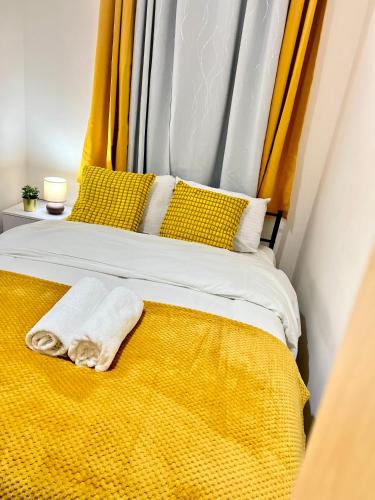 a bed with a yellow blanket and yellow pillows at The Brick Lane Suites London in London