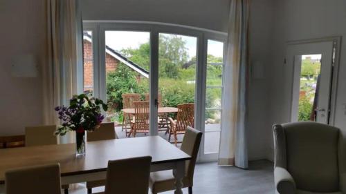 ein Esszimmer mit einem Tisch mit einer Vase mit Blumen in der Unterkunft Hof Rüsch - FeWo Bökenacker in Kesdorf