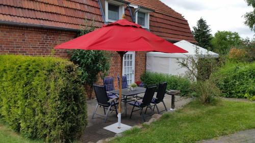 einen Tisch und Stühle unter einem roten Regenschirm im Hof in der Unterkunft Hof Rüsch - Bredensteen in Kesdorf