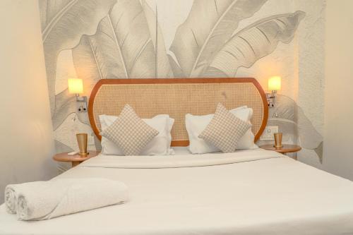 a bedroom with a white bed with pillows at Botanica Luxury 1BHK Apartment, Pool & Parking - Near Candolim Beach in Candolim