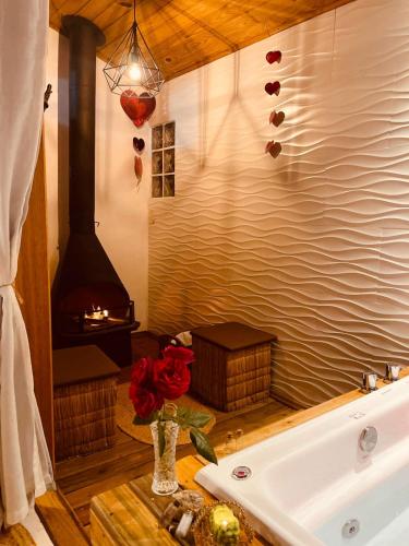 a bathroom with a tub and a vase with a rose at cabanas Aconchego dos Canyons in Praia Grande
