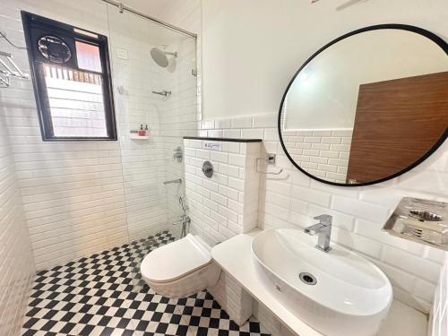 Un baño blanco con lavabo y espejo. en Modern Studio with Pool Access Near Candolim Beach - Balcony & Kitchenette, en Candolim