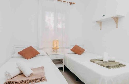 zwei Betten in einem Schlafzimmer mit weißen Wänden in der Unterkunft Espectacular Apartamento in Cala'n Bosch