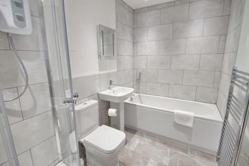 a bathroom with a toilet and a tub and a sink at Courtside Apartment Southsea in Portsmouth