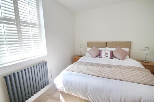 a bedroom with a bed with pink pillows and a window at Courtside Apartment Southsea in Portsmouth