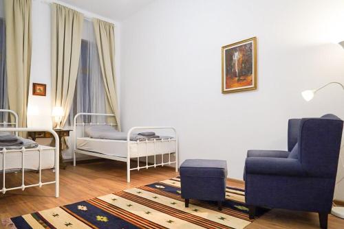 a living room with two beds and a blue chair at Central Serenity near Piata Unirii in Oradea