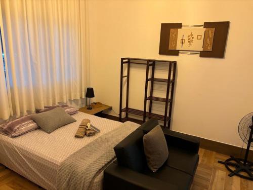 a bedroom with a bed with a chair and a clock at Loft 1 Elegante e Aconchegante Airport GRU in Guarulhos