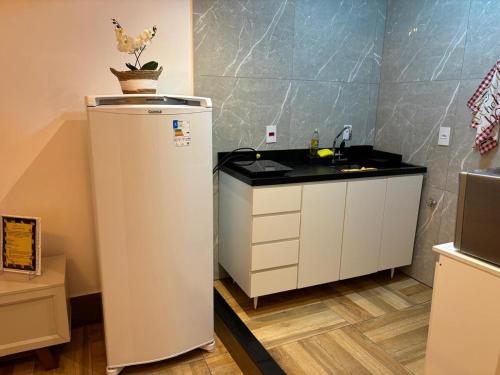 a small kitchen with a refrigerator and a sink at Loft 1 Elegante e Aconchegante Airport GRU in Guarulhos