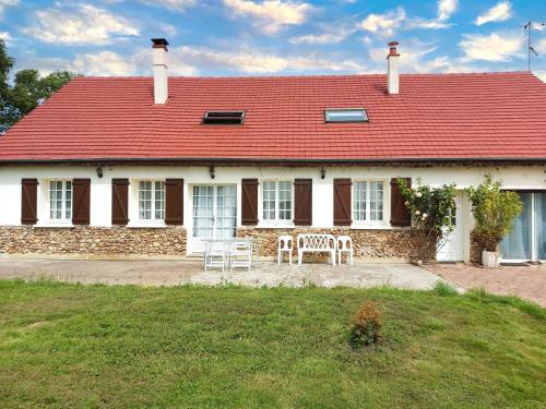 a house with a red roof and a table and chairs at Belle maison de Campagne Confortable avec piscine, pétanque etc 17 couchages in La Bazoche-Gouet