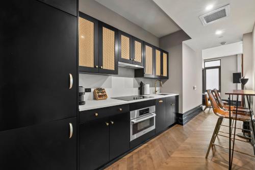 eine Küche mit schwarzen Schränken und einem Tisch in der Unterkunft Freeman 901 by Rove Studio with Shared Amenities in New York