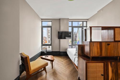 ein Schlafzimmer mit einem Bett, einem Stuhl und einem Fernseher in der Unterkunft Freeman 901 by Rove Studio with Shared Amenities in New York