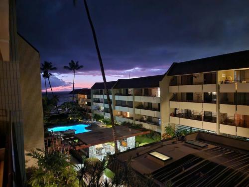 a view of a hotel with a swimming pool at night at Beachside Condo with Ocean Views in Kailua-Kona