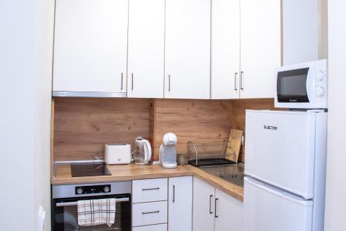 eine Küche mit weißen Schränken und einem weißen Kühlschrank in der Unterkunft !!!1min From The Lift I Luxury Studio In Pirin Palace in Bansko