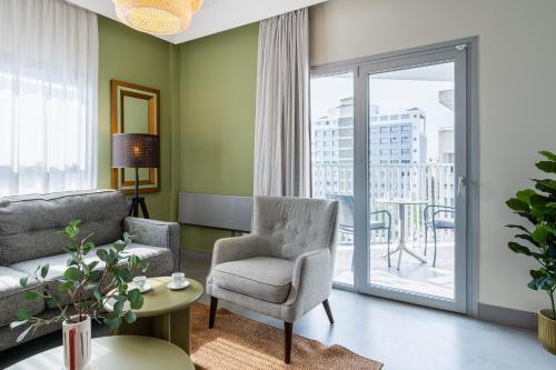 a living room with a couch and a chair and a window at Local Host Living - Signature Apartments in Nicosia in Nicosia