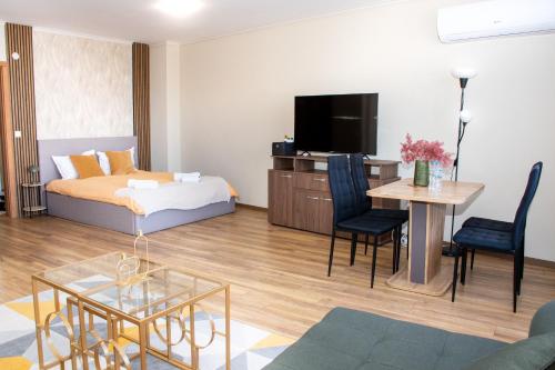ein Wohnzimmer mit einem Bett, einem Tisch und einem Fernseher in der Unterkunft !!!1min From The Lift I Luxury Studio In Pirin Palace in Bansko