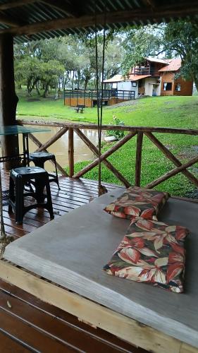 ein Bett auf einer Holzterrasse mit einem Tisch und Gras in der Unterkunft Pousada Caminho do Lago in Rio Rufino