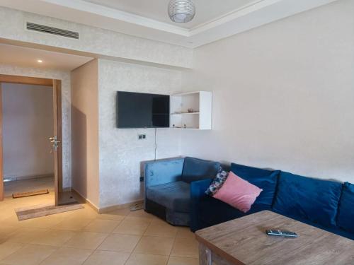 un soggiorno con un divano blu e una TV di Résidence Ebla a Minaret de Mansuria