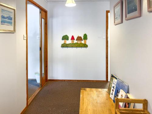 einen Flur mit einer weißen Wand mit Bäumen darauf in der Unterkunft Lorien Cottage in Nethy Bridge