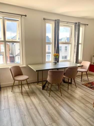 a dining room with a table and chairs and windows at home from home 2 bed flat in Kingston upon Thames
