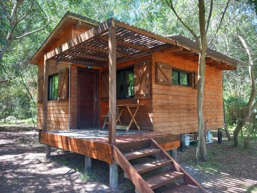 a wooden cabin in the woods with a porch at Cabaña monoambiente Yasyry in Las Toscas