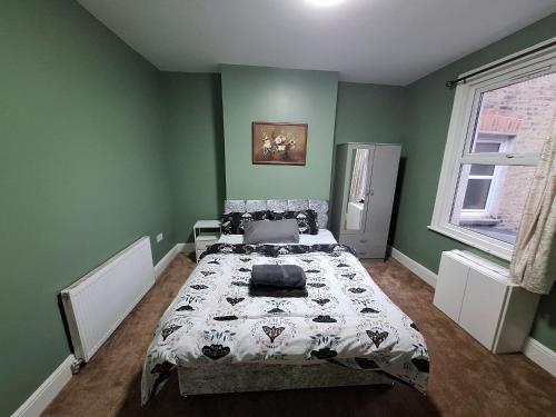 a bedroom with a bed in a green room at home from home 2 bed flat in Kingston upon Thames