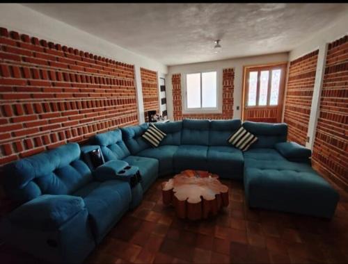 a living room with a blue couch and a brick wall at Cabañas Aruba in Zacatlán