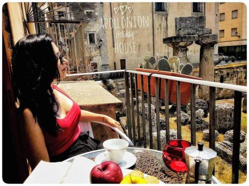 uma mulher sentada à mesa com uma chávena de café em Apollonion HH above Apollo's temple Ortygia em Siracusa