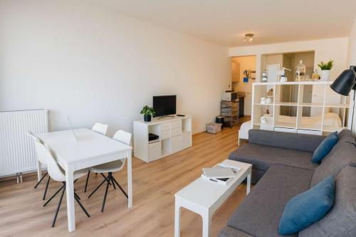 a living room with a couch and a table at Casiola - Beach Studio with Balcony & Sea View in Zeebrugge