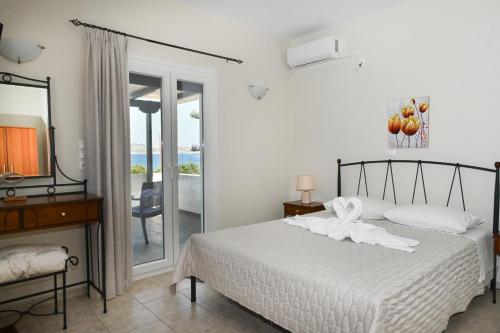 a bedroom with a bed with white sheets and a mirror at Akrothalassia in Adamantas