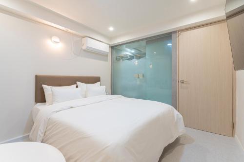 a bedroom with a large white bed and a glass door at 스테이쉼 발산 in Seoul