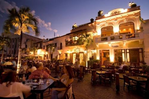 a group of people sitting at tables in front of a building at Tu rincon Caribeño in San Isidro