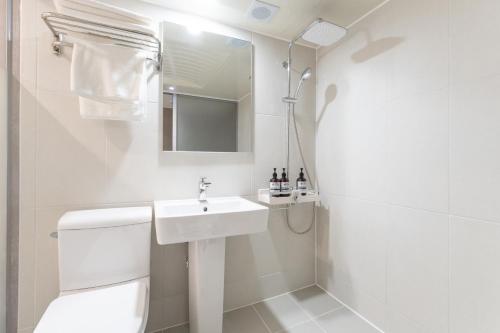 a white bathroom with a toilet and a sink at 스테이쉼 발산 in Seoul