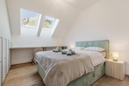 a white bedroom with a large bed with two pillows at Family Apartment Bovec with Free Parking in Bovec