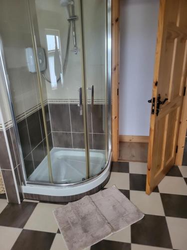 a shower stall in a bathroom with a checkered floor at Ard A Mhaoire in Glendorragha