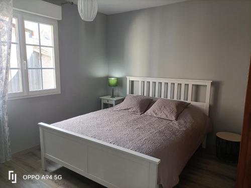 a bedroom with a white bed and a window at Le gîte du Coche avec vue sur la Marne in Damery