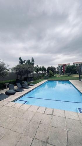 a large swimming pool with chairs around it at Luxury Fourways Apartment, Pool, Gym and 24hr Security - Ventura Estate in Sandton