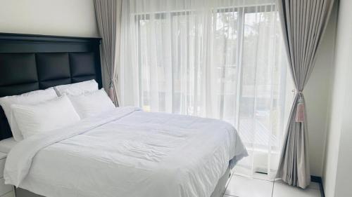 a bedroom with a white bed and a window at Luxury Fourways Apartment, Pool, Gym and 24hr Security - Ventura Estate in Sandton
