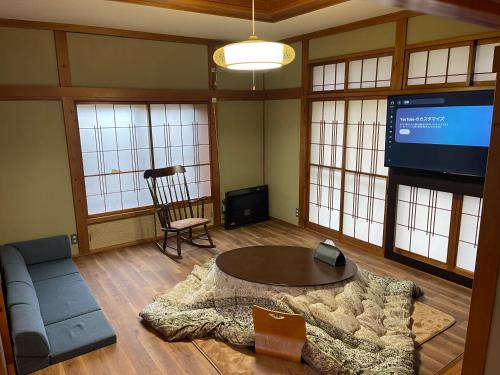 a living room with a couch and a table and a tv at 信の宿 花巻 in Hanamaki